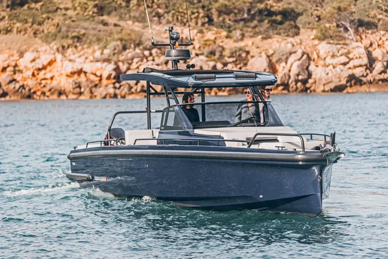 Slide: The Image of 2023 BRABUS Shadow 900 Deep Blue luxury boat cruising near rocky shoreline. - 26