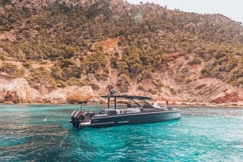 Slide: The Image of 2023 BRABUS Shadow 900 Deep Blue boat in clear turquoise water near rocky coastline. - 34