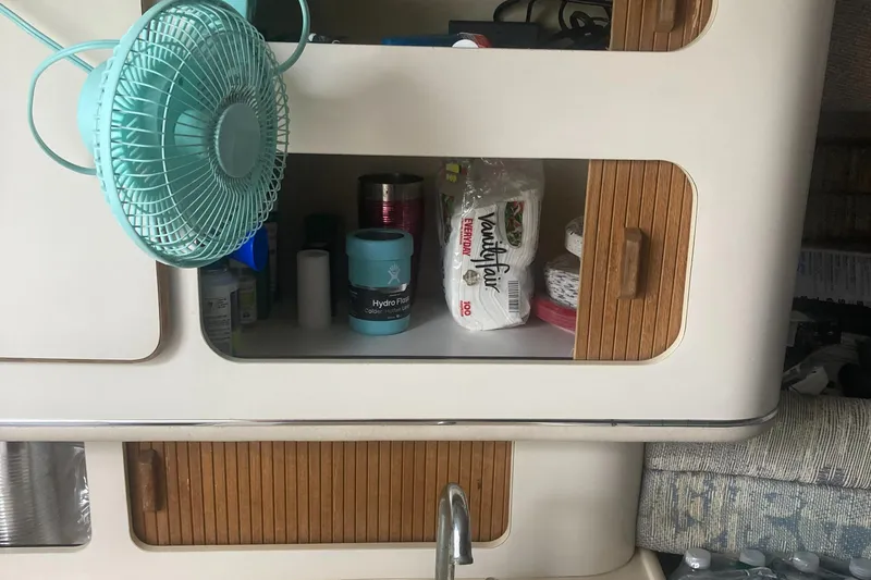 Slide: The Image of 1992 Sea Ray 300 Weekender interior with fan, storage, and supplies. - 12