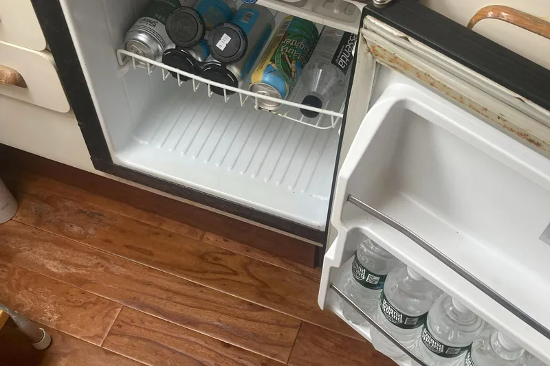 Slide: The Image of Mini fridge on 1992 Sea Ray 300 Weekender with drinks inside, wooden floor visible. - 13