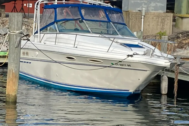 Slide: The Image of 1992 Sea Ray 300 Weekender boat docked in a marina, featuring blue trim and canopy. - 2