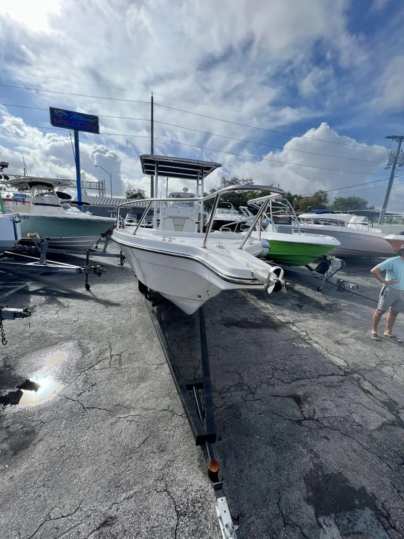 Slide: The Image of 2022 Wellcraft 220CC boat on trailer at a dealership under a cloudy sky. - 23