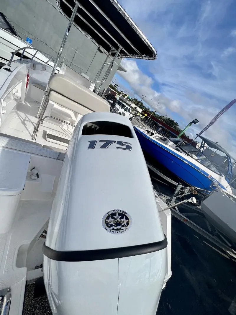Slide: The Image of 2022 Wellcraft 220CC boat with white seating, docked under a clear blue sky. - 34
