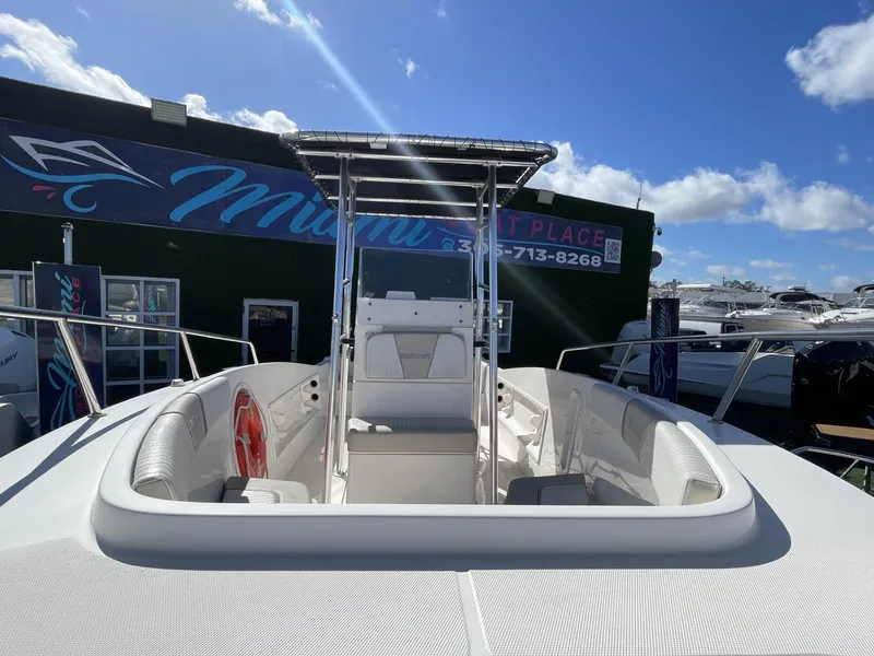Slide: The Image of 2022 Wellcraft 220CC center console boat at a dealership under a clear blue sky. - 7