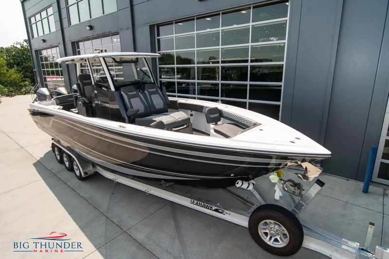 Slide: The Image of 2022 Fountain 32 NX boat on trailer outside building. - 2