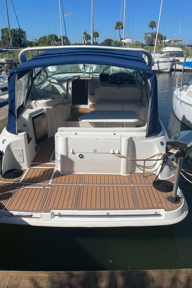 Slide: The Image of 1998 Cruisers Yachts 3375 Esprit docked, featuring spacious deck and blue canopy. - 3