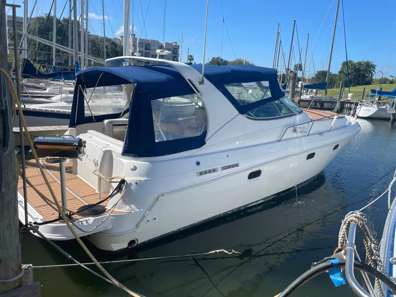 The Image of 1998 Cruisers Yachts 3375 Esprit docked in a marina, featuring a blue canopy. - 0