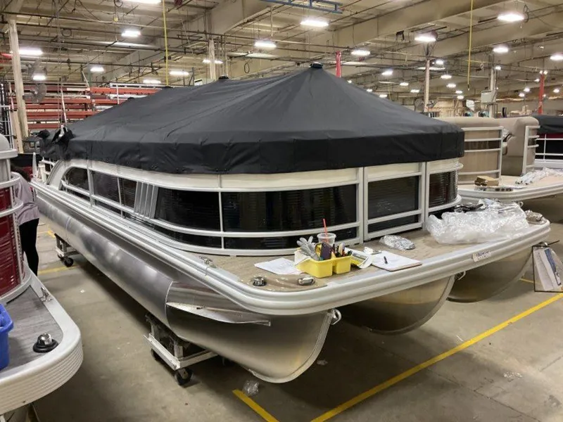 Slide: The Image of 2023 Bennington 23 LSR pontoon boat in a factory setting with a black cover. - 11