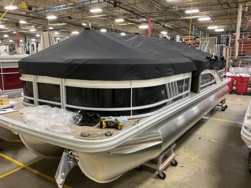 Slide: The Image of 2023 Bennington 23 LSR pontoon boat in a factory setting, covered with a black tarp. - 13