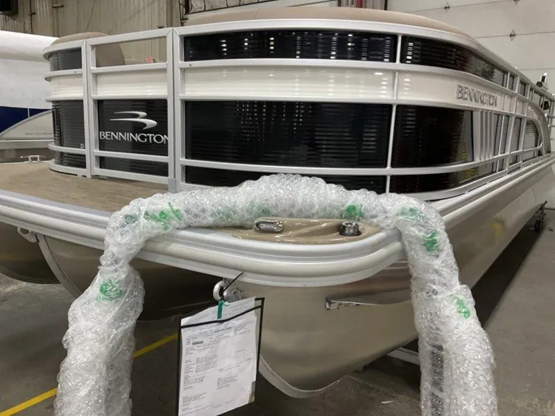 Slide: The Image of 2023 Bennington 23 LSR pontoon boat in a warehouse, partially wrapped in bubble wrap. - 9
