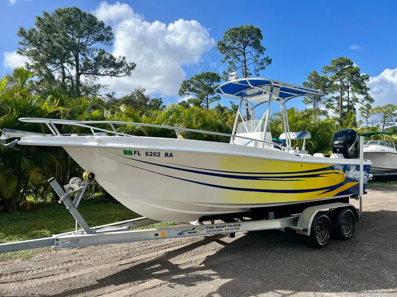 Slide: The Image of 2016 Renegade 250 boat on trailer with yellow and blue accents, parked outdoors. - 2