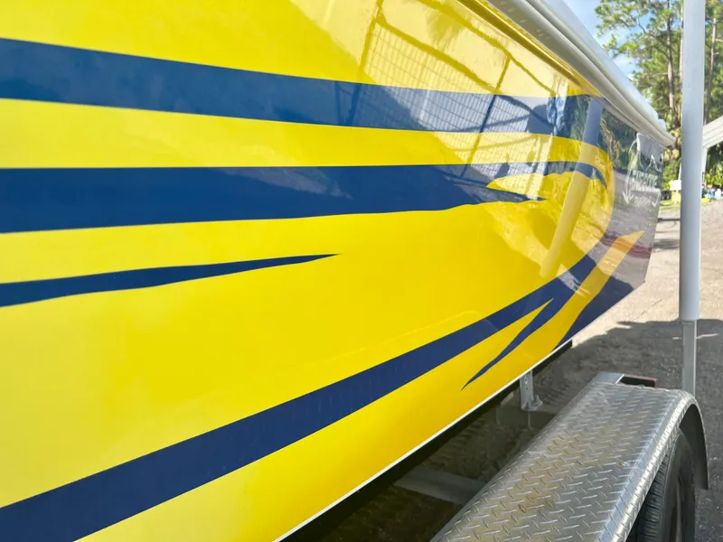 Slide: The Image of Yellow 2016 Renegade 250 boat with blue stripes on a trailer. - 23