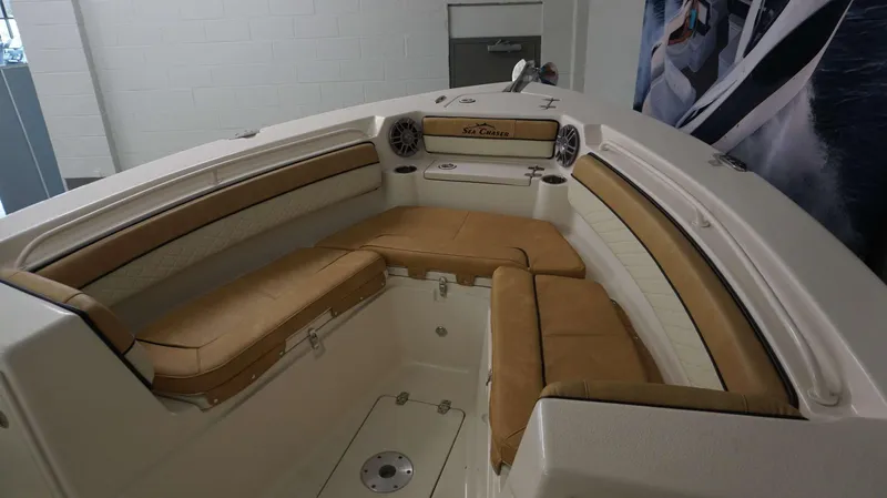 Slide: The Image of 2023 Sea Chaser 27 HFC boat interior with tan cushioned seating and built-in speakers. - 24