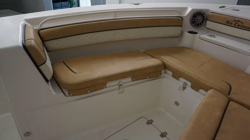 Slide: The Image of 2023 Sea Chaser 27 HFC boat interior with tan cushioned seating and storage compartments. - 28