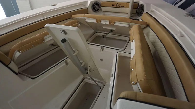 Slide: The Image of 2023 Sea Chaser 27 HFC boat interior with tan cushioned seating and storage compartments. - 7