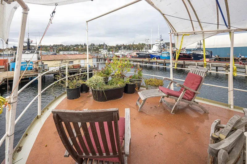 Slide: The Image of Deck of 1943 Custom Navy Tug with chairs and potted plants, overlooking a marina. - 12