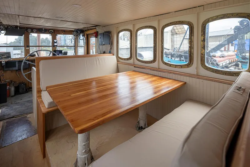 Slide: The Image of Interior of a 1943 Custom Navy Tug with wooden table and cushioned seating. - 15