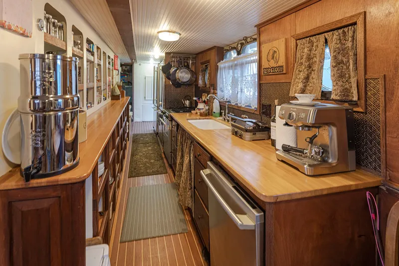 Slide: The Image of Galley kitchen inside a 1943 custom Navy tugboat, featuring wooden cabinetry and modern appliances. - 17