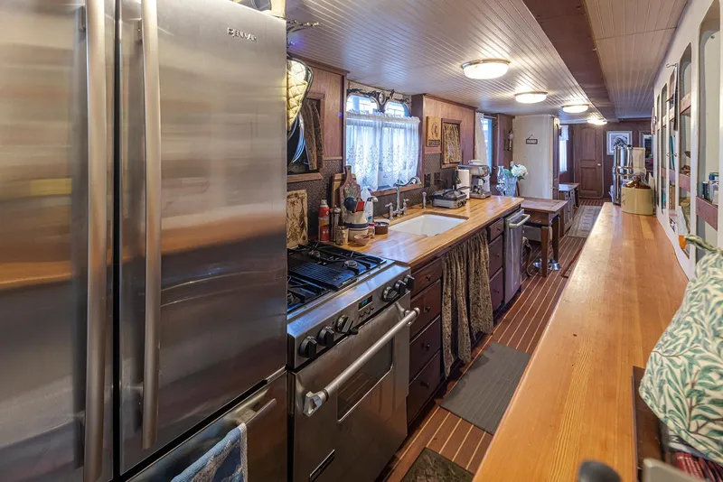 Slide: The Image of Kitchen interior of a 1943 Custom Navy Tug, featuring modern appliances and wooden countertops. - 19