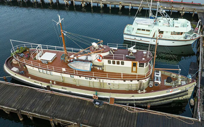 Slide: The Image of Custom 1943 Navy Tugboat docked at a marina, with a vintage design and wooden deck. - 2