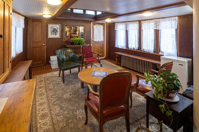 Slide: The Image of Cozy 1943 Navy Tug interior with vintage furniture, wooden paneling, and decorative plants. - 24