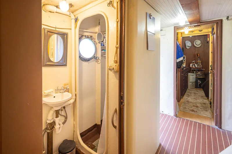 Slide: The Image of Interior of a 1943 Custom Navy Tug, featuring a compact bathroom and hallway. - 27