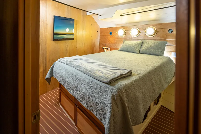 Slide: The Image of Cozy bedroom in a 1943 Custom Navy Tug, featuring a bed, portholes, and nautical decor. - 29