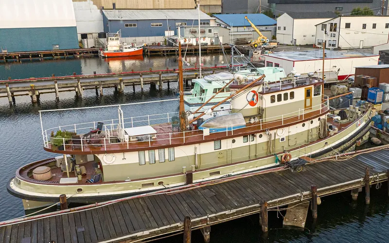Slide: The Image of Historic 1943 Custom Navy Tugboat docked at a marina, surrounded by industrial buildings. - 3