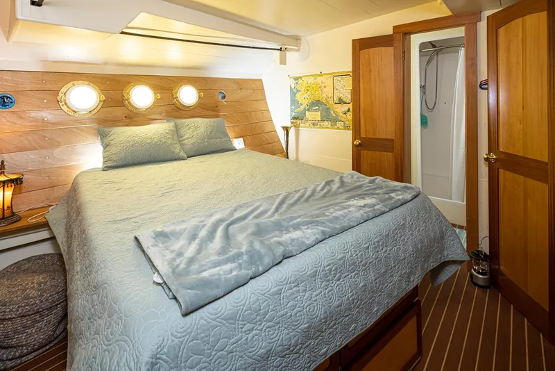 Slide: The Image of Cozy bedroom in a 1943 custom Navy tugboat with nautical decor and porthole windows. - 30