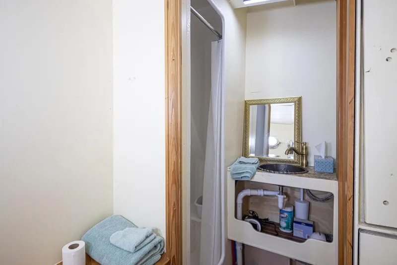Slide: The Image of Small bathroom with shower, sink, mirror, and towels on a 1943 Custom Navy Tug. - 32