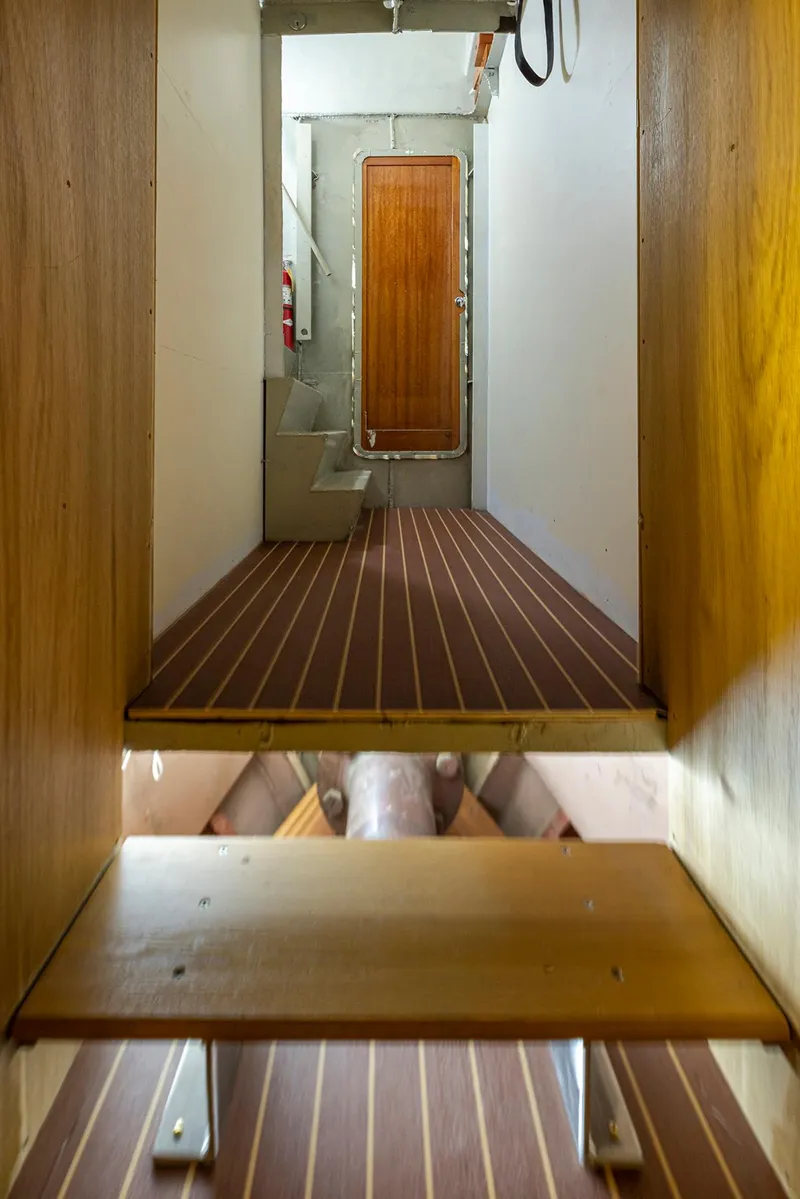 Slide: The Image of Interior view of a 1943 Custom Navy Tug with wooden flooring and a closed door. - 36