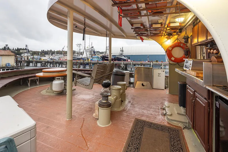 Slide: The Image of 1943 Custom Navy Tugboat deck with seating, kitchen area, and harbor view. - 6