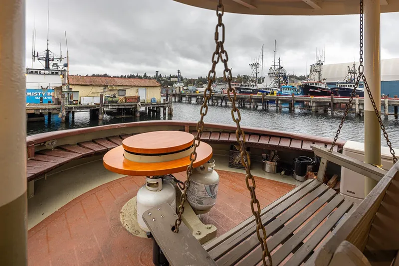 Slide: The Image of 1943 Custom Navy Tugboat deck with benches, chains, and harbor view. - 7