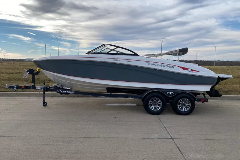 The Image of 2023 Tahoe 210 Si boat on trailer, parked on concrete, under cloudy sky. - 0