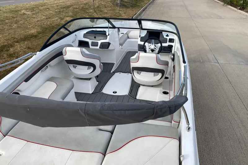 Slide: The Image of 2023 Tahoe 210 Si boat interior with seating and steering wheel, parked on pavement. - 11