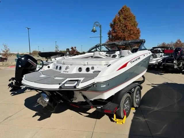 Slide: The Image of 2023 Tahoe 210 Si boat on trailer, parked on a paved surface under a cloudy sky. - 2