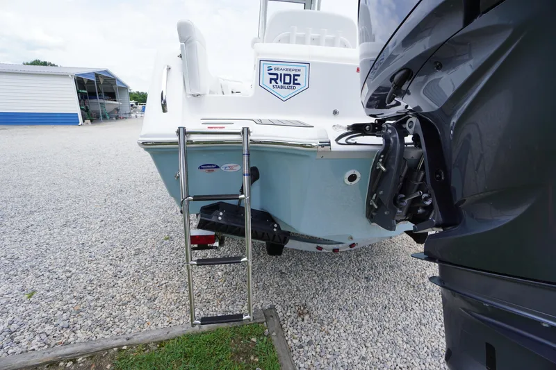 Slide: The Image of 2026 Tidewater 232 SS boat with ladder and outboard motor, parked on gravel. - 74