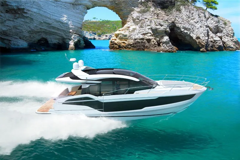 Slide: The Image of 2023 Galeon 450 HTC yacht cruising in turquoise waters near rocky arch. - 1