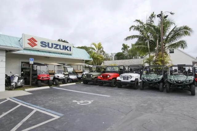 Slide: The Image of Suzuki dealership with various off-road vehicles parked outside. - 23