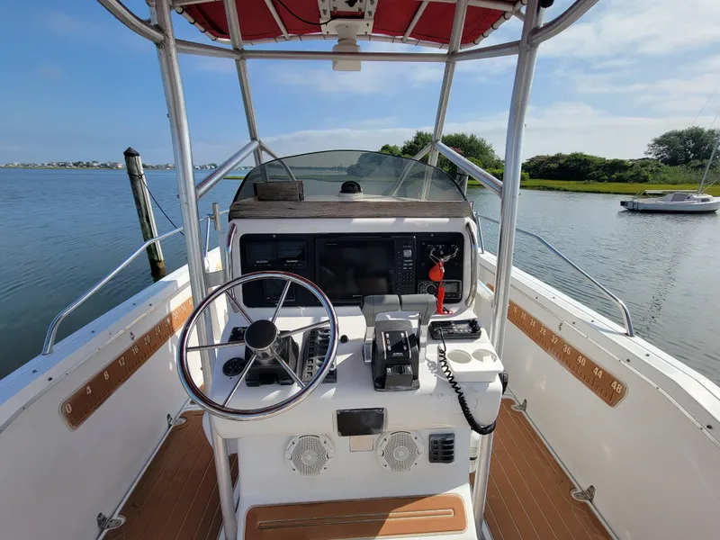 Slide: The Image of 1997 Glacier Bay 260 Canyon Runner boat cockpit with steering wheel and controls on a calm lake. - 9