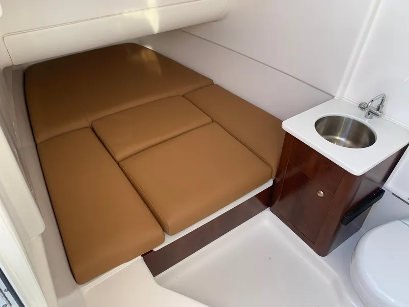 Slide: The Image of 2024 Robalo R360 cabin interior with brown cushioned bed and small sink. - 20