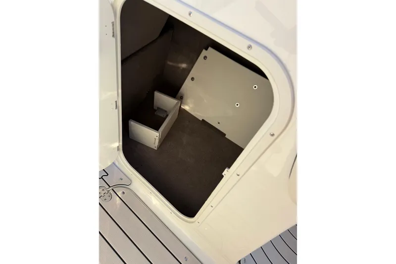 Slide: The Image of 2022 Stingray 235 LR boat storage compartment with open hatch and carpeted interior. - 15
