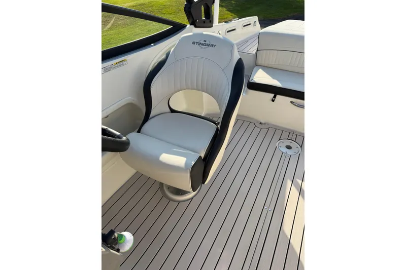 Slide: The Image of 2022 Stingray 235 LR boat interior with white captain's chair and sleek deck design. - 23