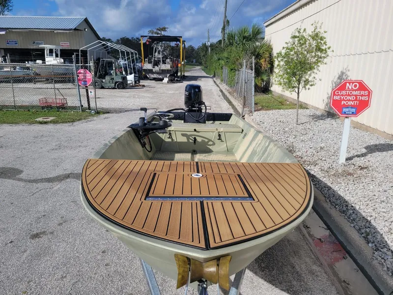 Slide: The Image of 2021 Hog Island Boat Works SW16 on trailer, wooden deck, outboard motor, industrial background. - 2
