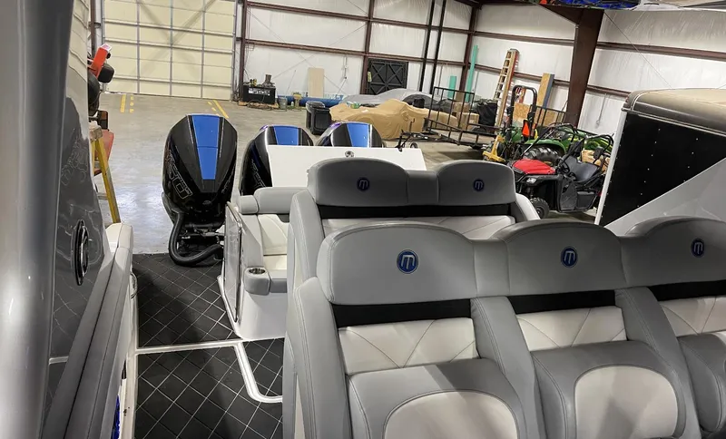 Slide: The Image of 2020 Mystic 3800 boat interior with seating and dual outboard motors in a warehouse. - 22