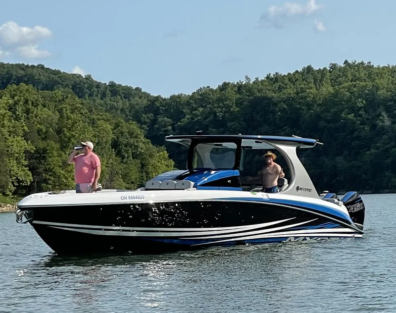 Slide: The Image of 2020 Mystic 3800 boat cruising on a lake with two people onboard. - 3