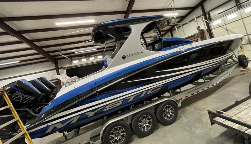 Slide: The Image of 2020 Mystic 3800 powerboat in a warehouse, blue and white design, on a trailer. - 5