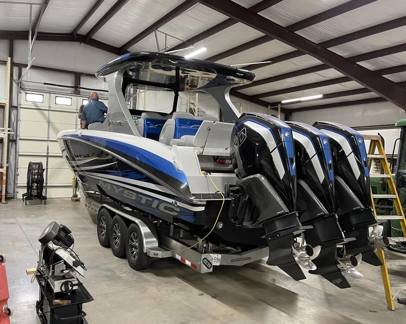 Slide: The Image of Mystic 3800 2020 model boat with triple outboard engines in a warehouse. - 8