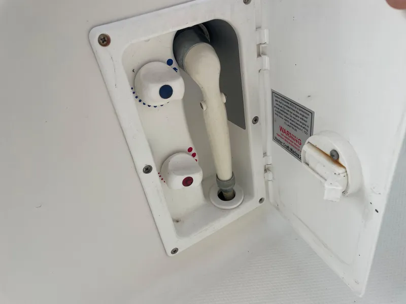Slide: The Image of 2006 Sea Ray 270 Amberjack boat shower controls and hose in white compartment. - 44