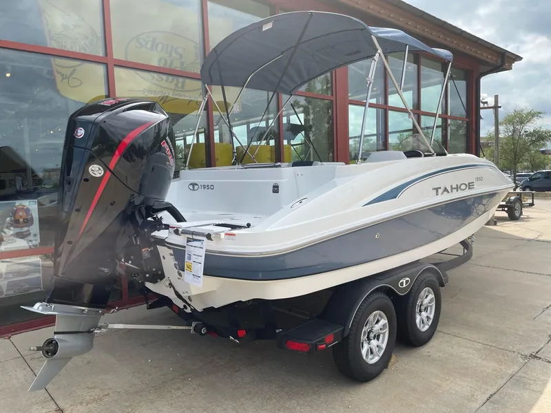 Slide: The Image of 2023 Tahoe 1950 boat with outboard motor and trailer, parked outside a showroom. - 4